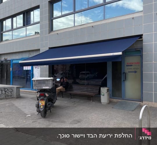 סוכך זרועות מתקפל כחול מותקן בחזית בית עסק